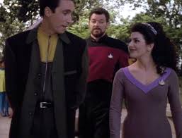 Conor and Troi talk while Riker walks behind them