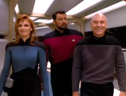 Picard and Crusher walking in front of Riker and brain sharing.