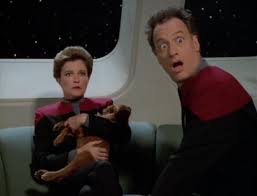Janeway holding a puppy and Q being surprised as fuck