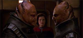 The two aliens talking over Janeway